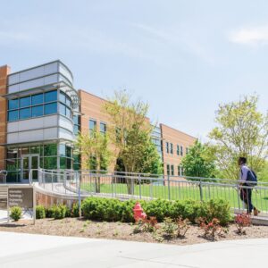 Image of a building on UMBC's campus with a student with a backpack approaching on a walkway.